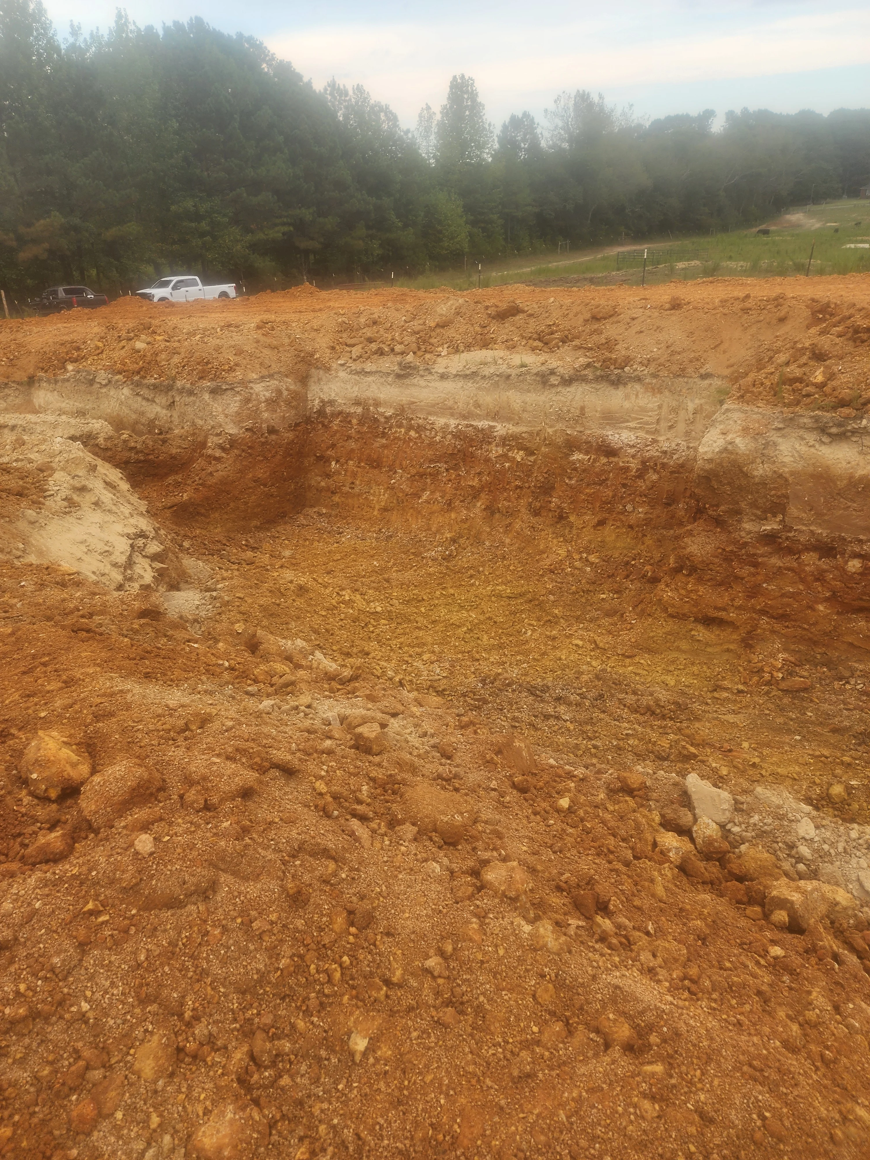 Excavated residential lot with reddish clay soil and stockpiled earth material