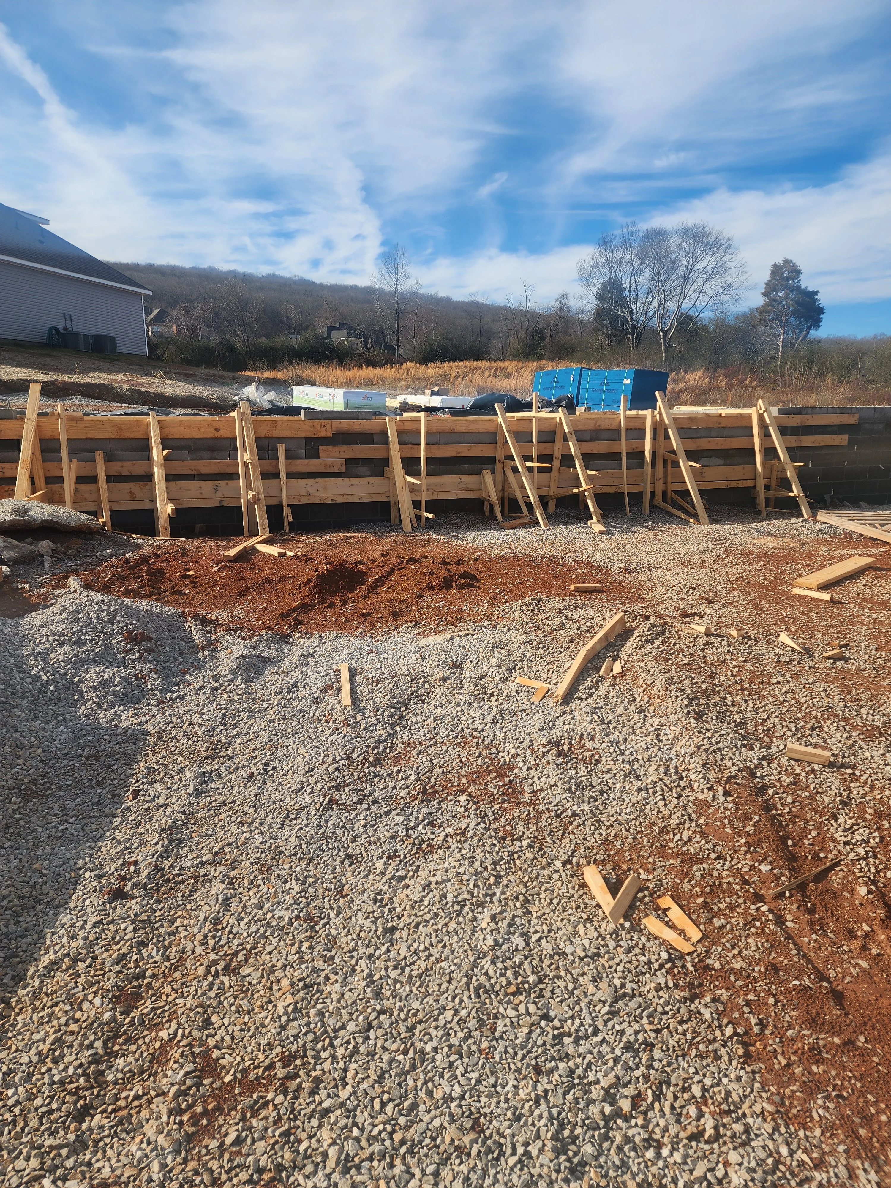 Timber retaining wall foundation with gravel base and wooden bracing during excavation phase