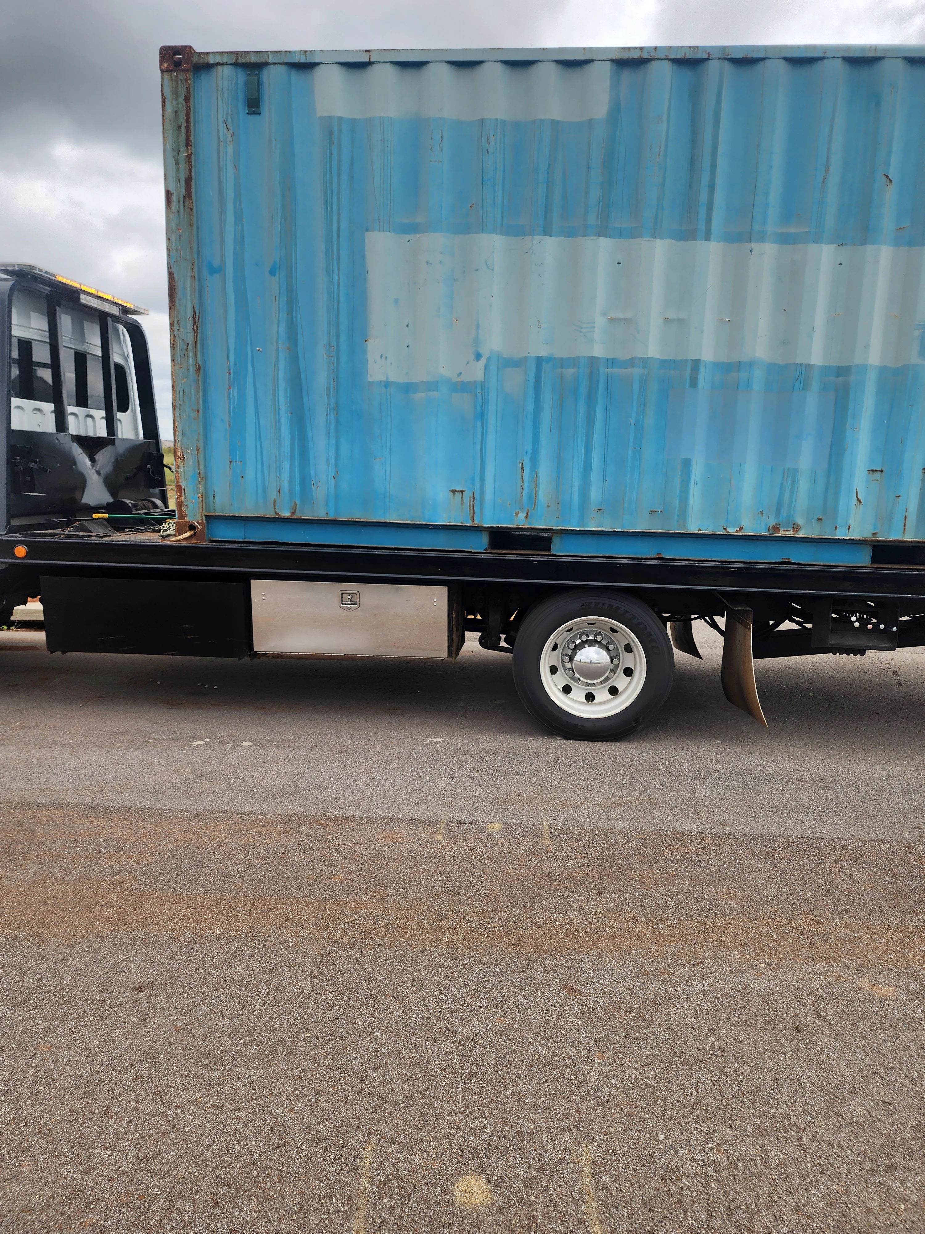 Blue and white corrugated metal truck box mounted on commercial flatbed trailer