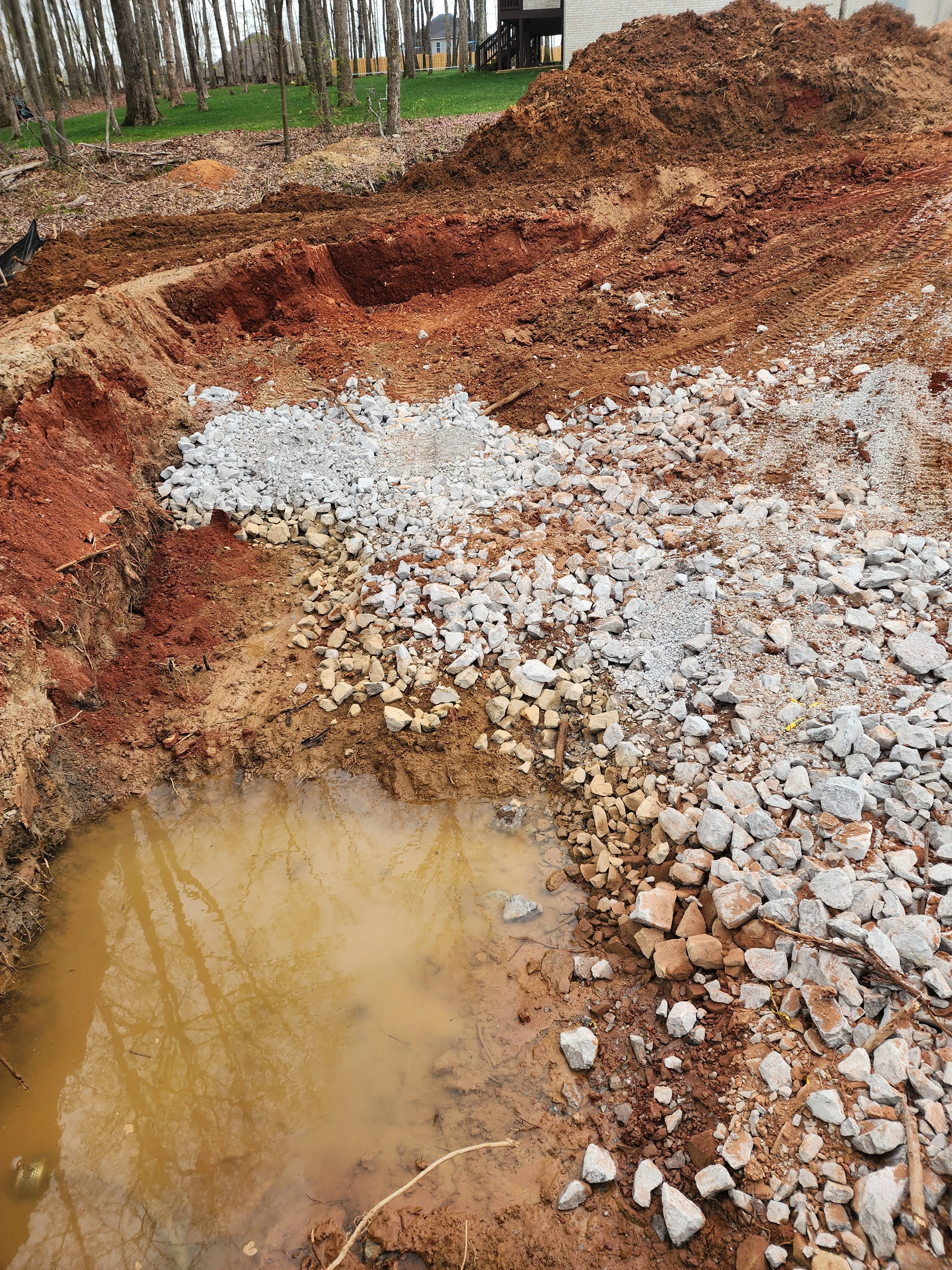 Excavated foundation pit with white stone and gravel drainage base layers