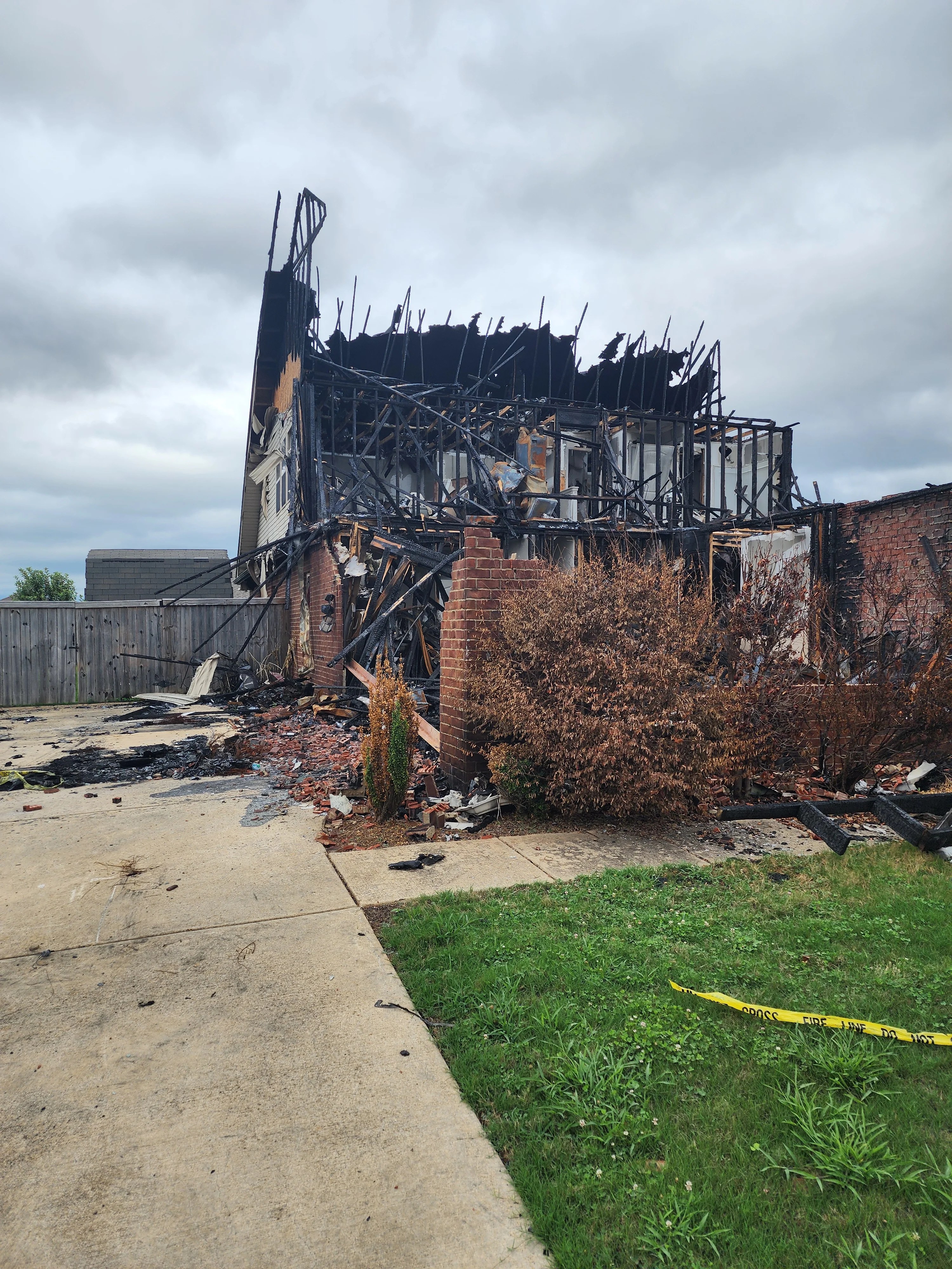Demolished fire-damaged brick commercial building with exposed steel frame and debris