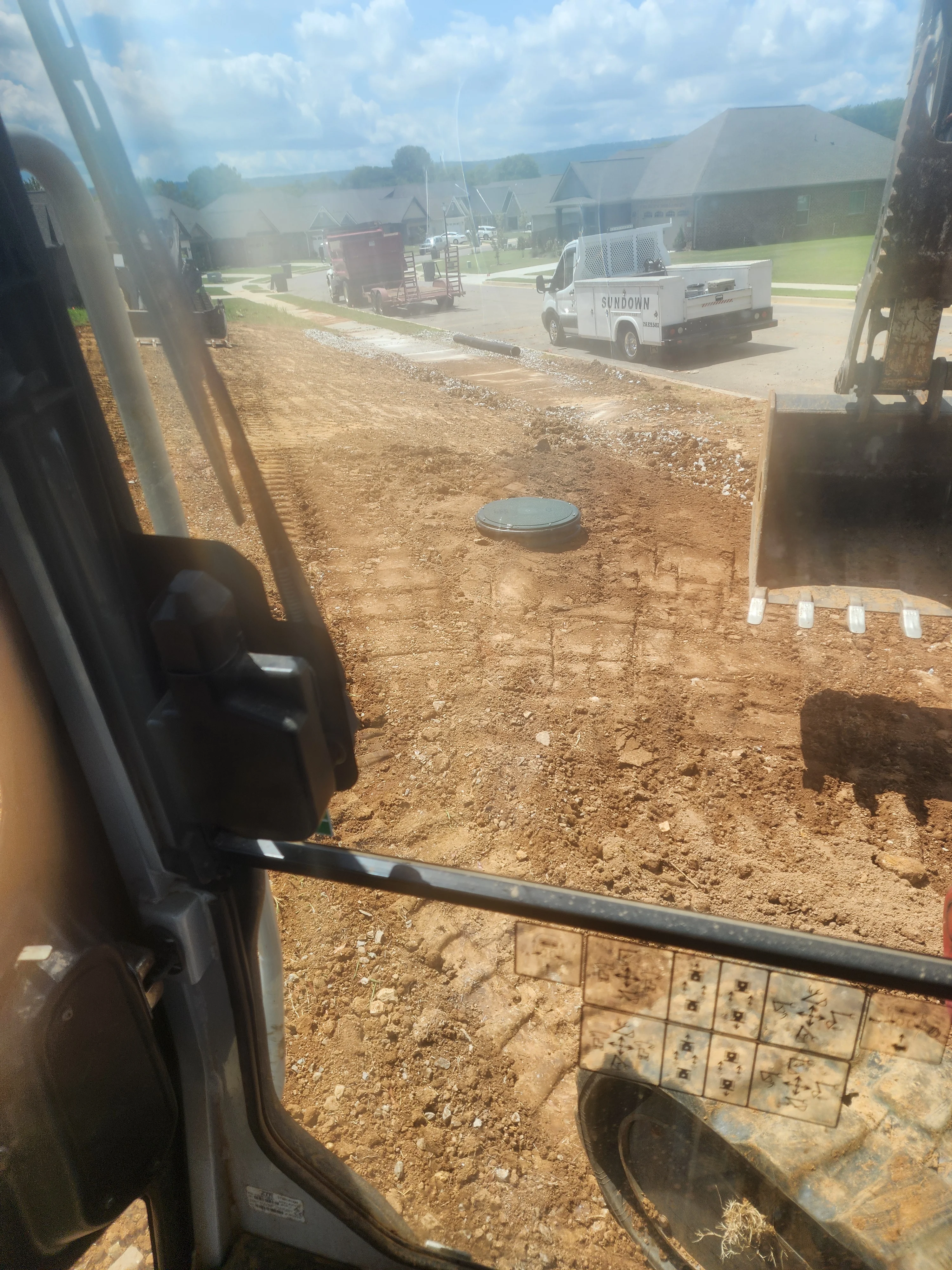 Excavated septic system installation site with metal tank and drainage field markers