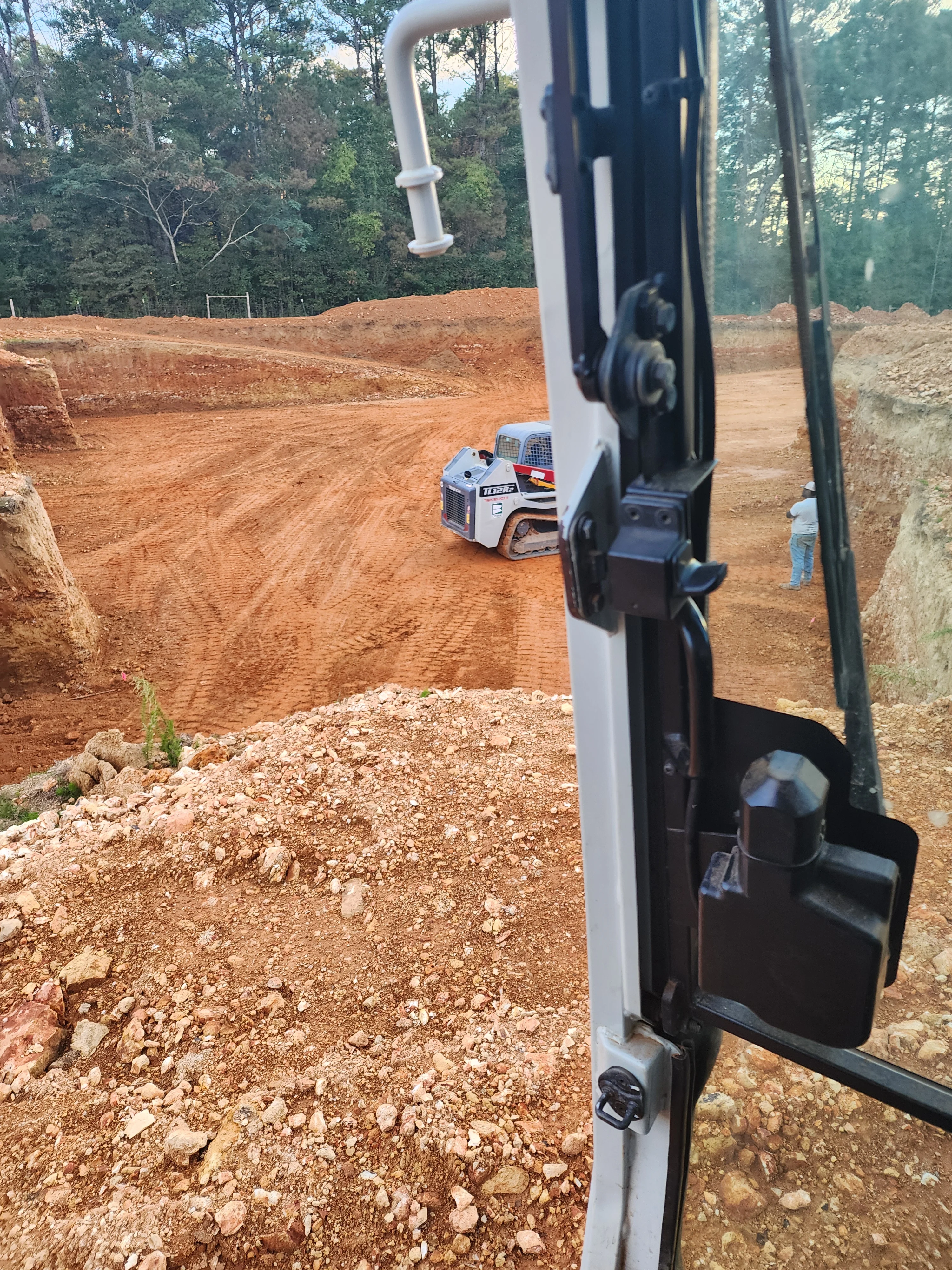 Skid steer loader grading red clay soil on cleared residential excavation site