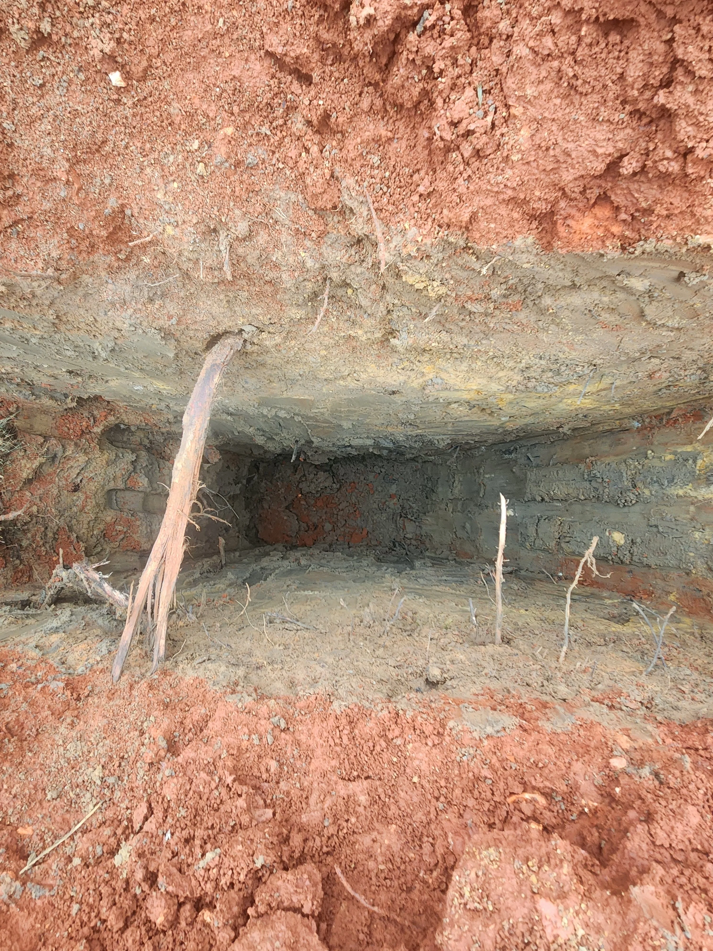 Excavated foundation pit with layered soil and concrete footer visible