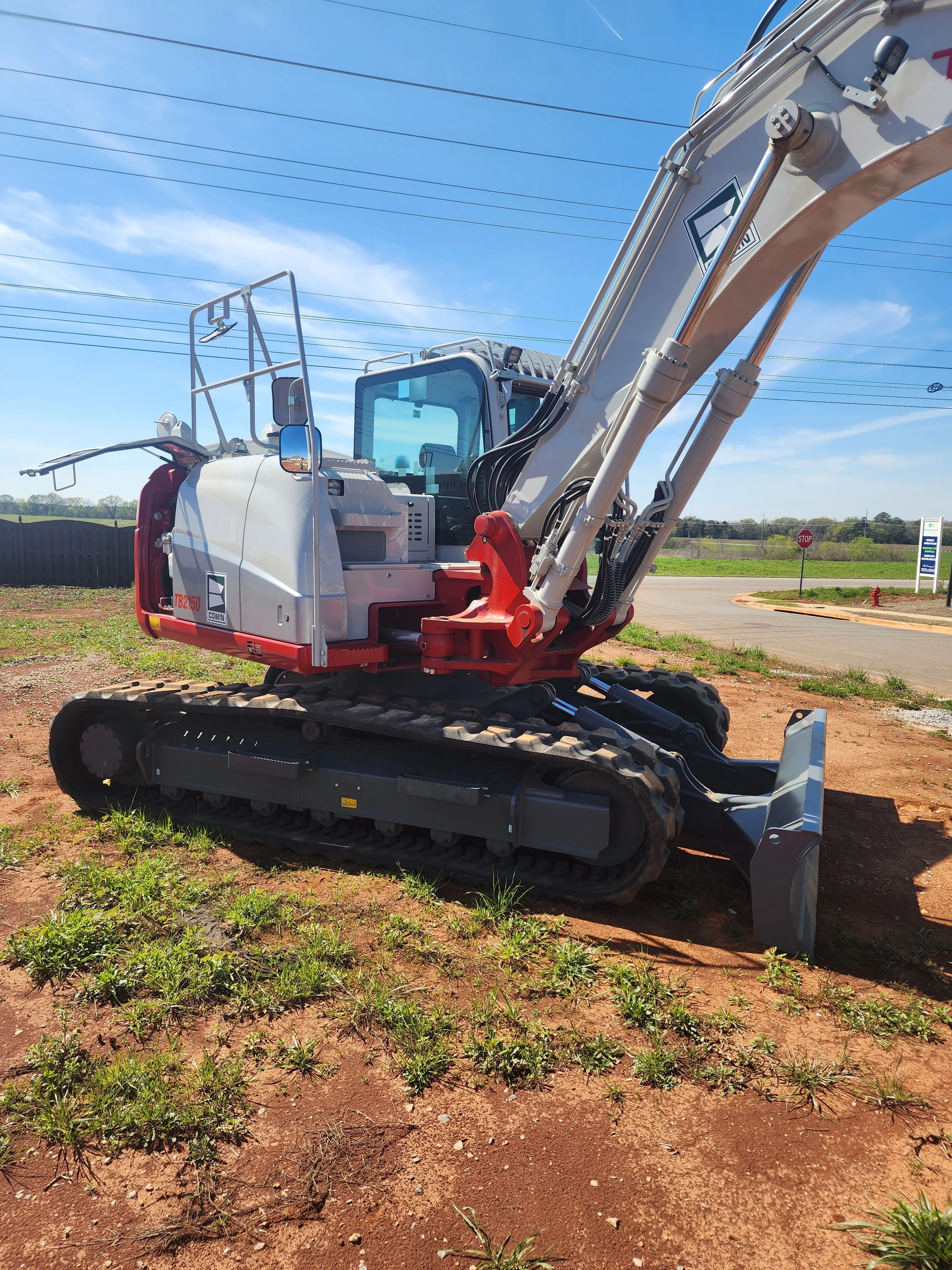 Compact track excavator with red thumb attachment positioned on dirt lot in Toney, Alabama