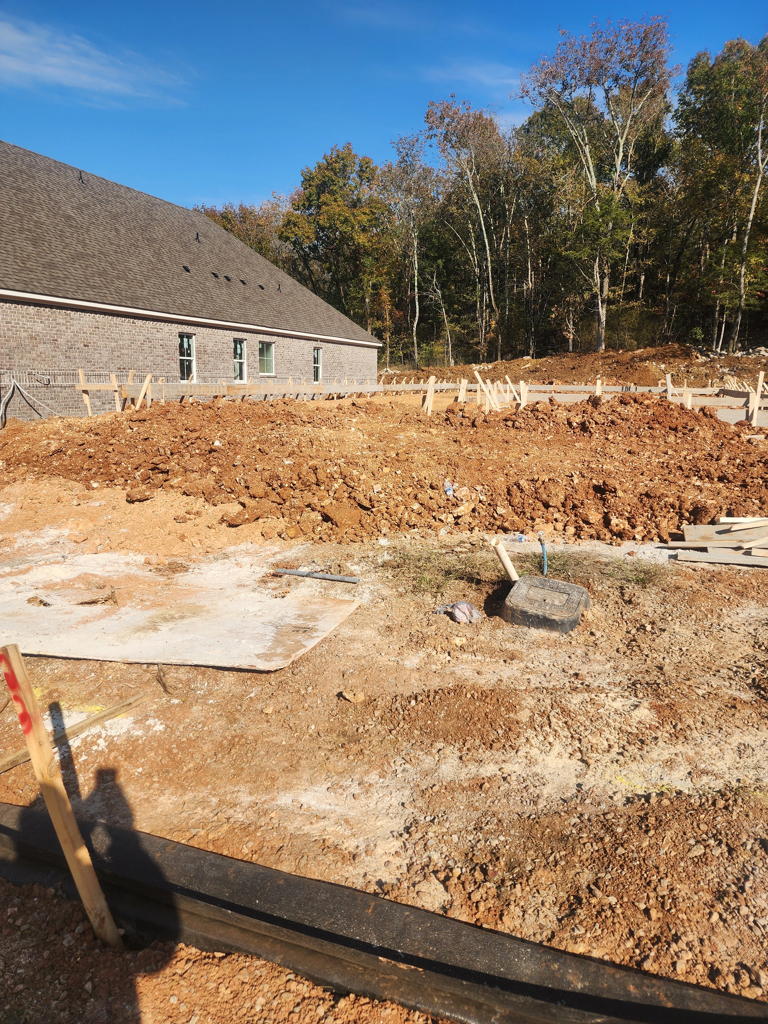 Excavated residential lot with brick home foundation and graded earth work in progress